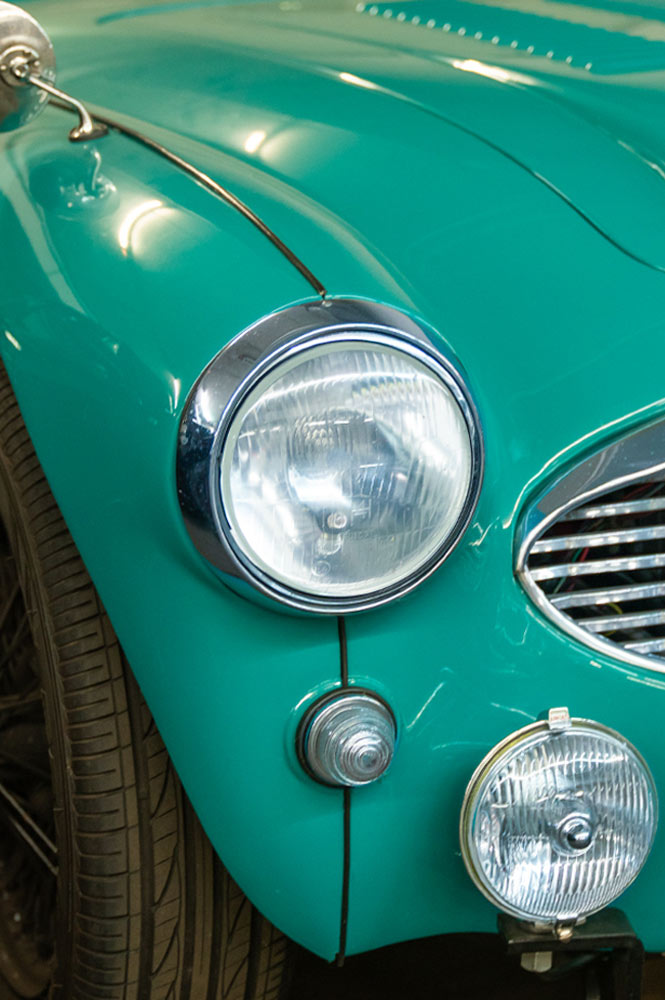 Die linken Frontscheinwerfer eines grünen Oldtimers